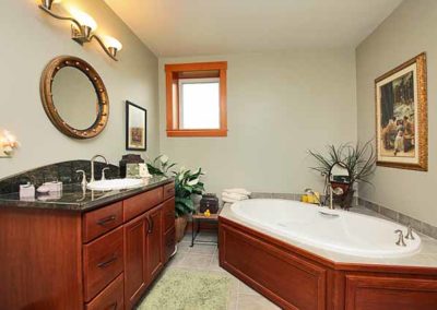 Spacious bathroom with a big bathtub and black granite sink countertop