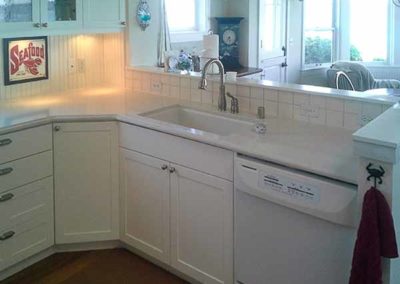 Kitchen corner with a sink, dishwasher, and white countertops