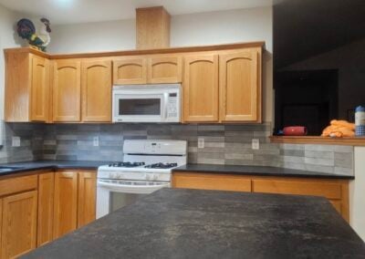 Modern kitchen renovation featuring wooden cabinets, a gas stove, and a stylish backsplash, showcasing NorthWest Granite & Flooring LLC's expertise in home remodeling.