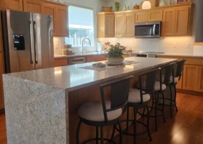 Modern kitchen renovation featuring slab countertops, wooden cabinetry, and a spacious island with seating, showcasing the expertise of NorthWest Granite & Flooring LLC.