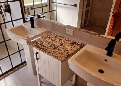 Modern bathroom remodel featuring dual sinks with stylish black faucets, a granite countertop, and contemporary cabinetry, showcasing NorthWest Granite & Flooring LLC's renovation expertise.