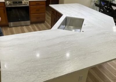 Modern kitchen countertop with integrated sink, featuring elegant white marble design and wooden cabinetry in the background, showcasing NorthWest Granite & Flooring LLC's renovation expertise.