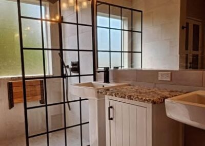 Modern bathroom renovation featuring a sleek glass shower enclosure, dual sinks with granite countertops, and stylish fixtures, showcasing NorthWest Granite & Flooring's design expertise.